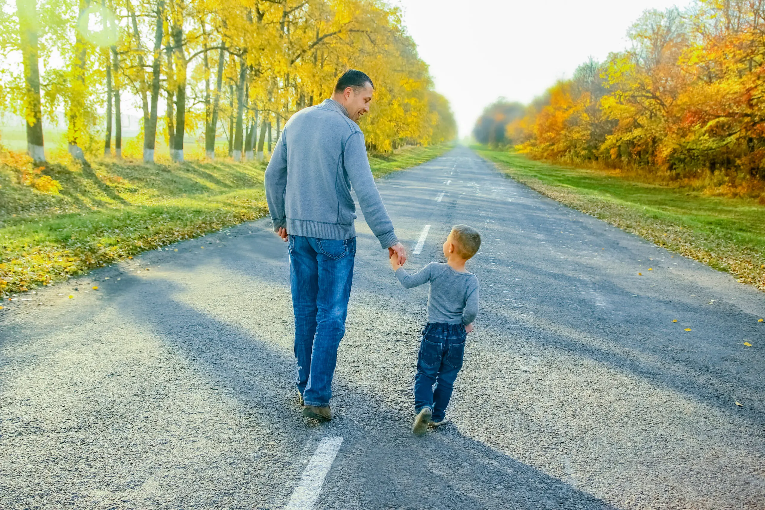 Father walking down road with son holding hands