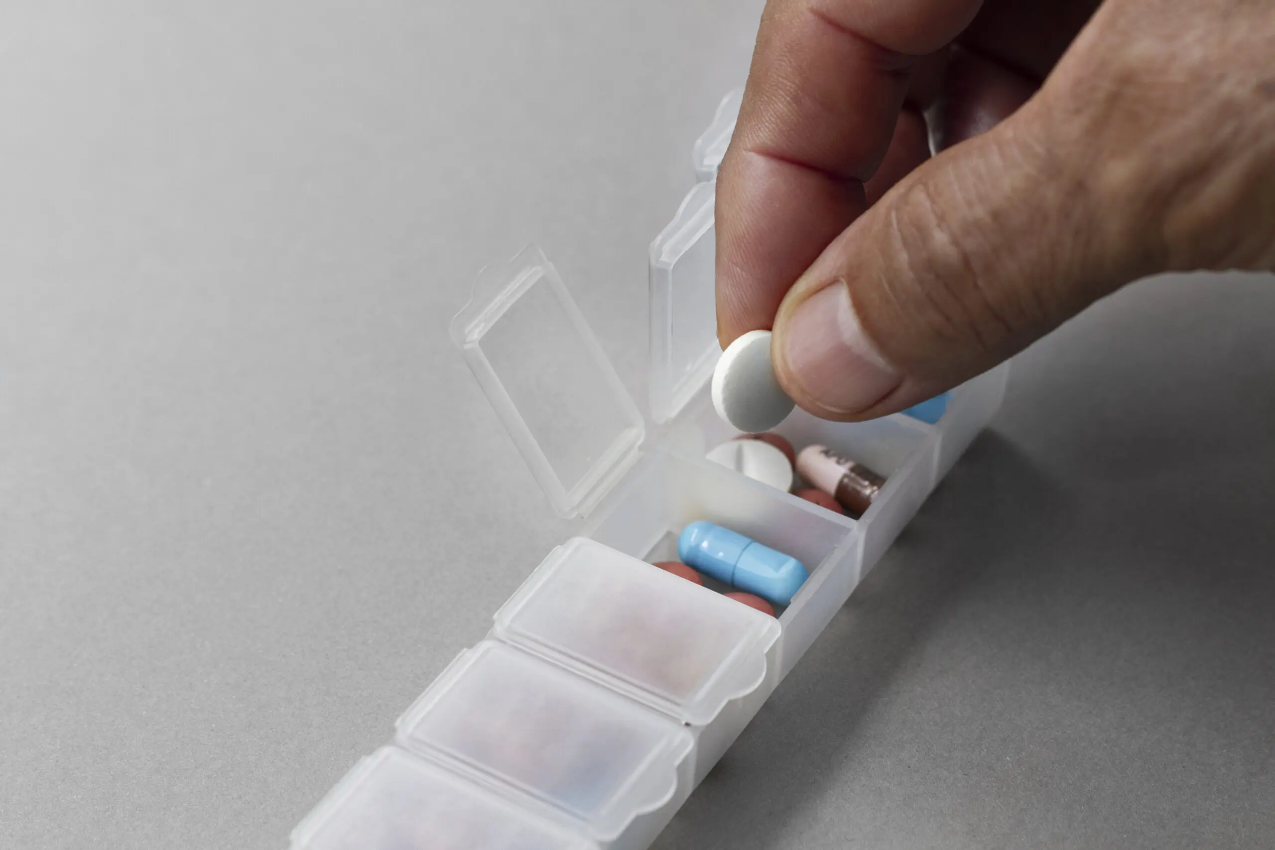 someone placing pills into an organization