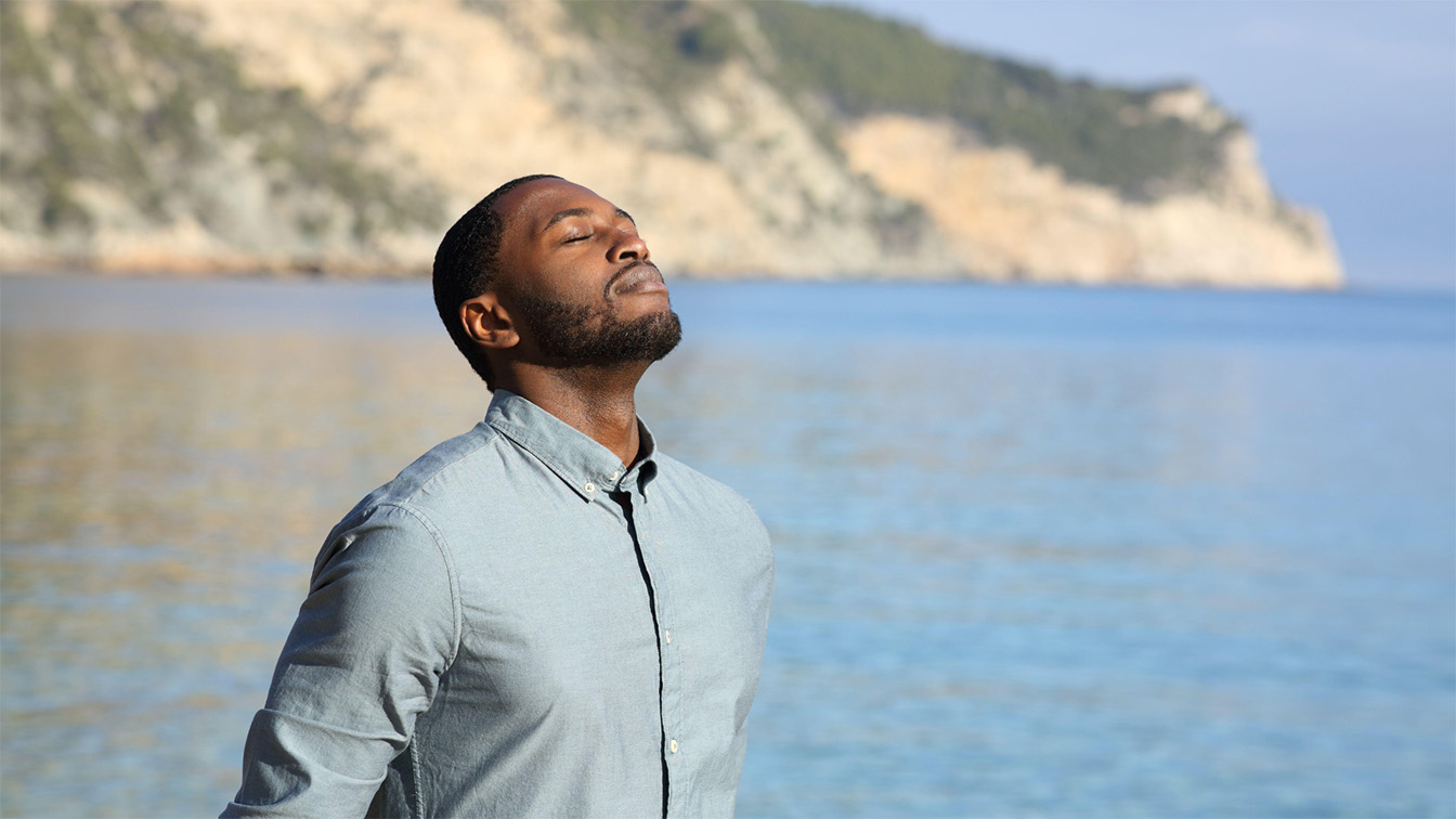 Man breathing deeply on the shore of the Upper Peninsula, representing respiratory health and asthma management by HNJH specialists_ Man breathing deeply on the shore of the Upper Peninsula, representing respiratory health and asthma management by HNJH specialists.