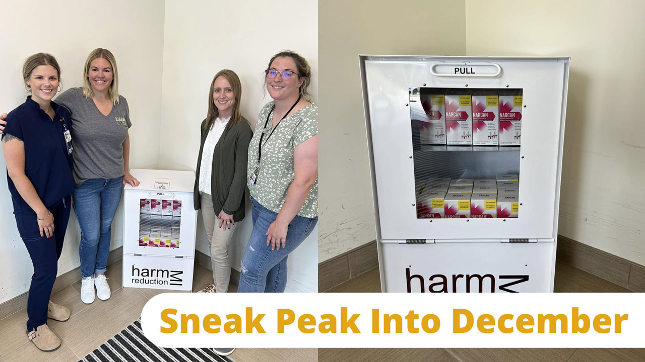 HNJH staff standing next to a Narcan distribution box inside Helen Newberry Joy Hospital highlighting community harm reduction and overdose prevention efforts